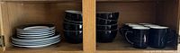 Stacked plates, bowls and mugs inside cabinet