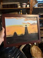 Front view of framed painting showing lighthouse sunset scene