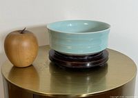 Celadon brush washer on wood stand next to apple for scale