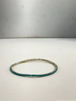 Full view of turquoise stone tennis bracelet laid flat
