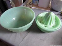 Two jadeite bowls and uranium glass juicer on table
