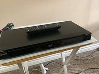 Front view of Sony Blu-ray/DVD player with remote placed on top