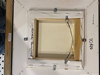 Back of painting showing canvas, stretcher, wire hanger, artist name and size notation