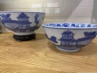 Both blue and white porcelain bowls side by side showing exterior landscape motif