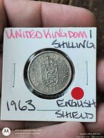 Coin in cardboard holder showing reverse English shield side with date 1963