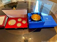 Cup in blue case beside cased medallion set, overall view