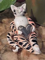 Front view of reclining ceramic cat figurine holding heart