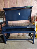 Full view of blue steel Mastercraft workbench showing pegboard, upper shelf, work surface, lower drawer and frame