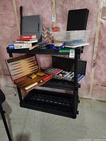 Full view of three-tier black plastic shelf with items placed on top for scale