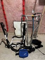 Multiple mobility aids and therapy devices grouped: walker, quad cane, transfer assist frame, cushion, wrist braces, electronic devices with cases