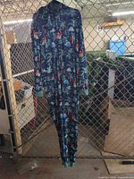 Front view of navy dinosaur print fleece onesie hanging to show full length, zipper, hood, cuffs and pockets