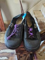 Top view of both black canvas sneakers with purple bungee laces and O'Neill insoles visible