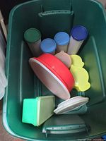 assorted Tupperware canisters, bowls, containers and lids inside a green tote