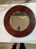 Front view of round mahogany sun motif mirror