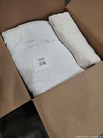 White monogrammed bath towel and rolled white towel in box
