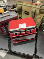 Red AirLok cooler front with shoulder strap; tan Yeti and maroon Yeti coolers in background