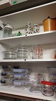 Cabinet view showing storage containers, measuring cups and bowls