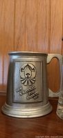 Front view of pewter beer stein showing inscription and emblem
