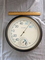 Front view of AcuRite 12-inch analog thermometer and hygrometer with ruler for scale