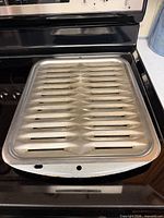 Stainless steel broiler pan slotted top resting on stove surface