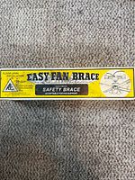 Box labelled Easy Fan Brace Electrical Safety Brace by Reiker Enterprises lying on carpet