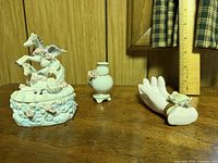 Trio of porcelain items: horse-topped trinket box, bud vase, hand ring holder