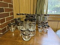 Full grouping of clear glasses with silver rims arranged on wooden surface