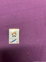 Front view of rectangular Rangers logo enamel pin on purple background