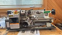 Full view of Craftex CX704 lathe with chuck, tailstock, compound rest, manual and tooling on base