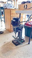 Full view of Delta mortiser with base, column, motor, lever, accessories nearby