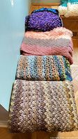 Four folded afghans stacked, showing colors and textures