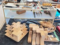 Shelf with carving tools on top and below plus wood blanks, plaque and handles displayed