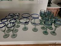 Full set of margarita and goblet glasses arranged on counter