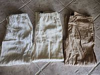 Three pairs linen trousers laid flat showing colors and styles