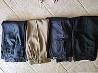 Four folded pairs of dress pants in various colors