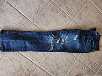 Full view of folded jeans showing overall color, length, distressing