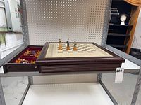 Chess board on shelving with drawer open showing some figurine pieces