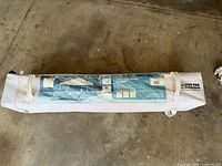 Canopy inside white wheeled carry bag lying on floor