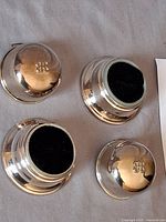 Four silver-plated pin cushion holders showing tops with two felt inserts visible
