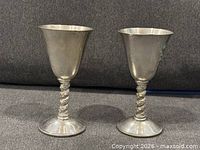 Two silver-plated goblets standing upright on gray surface