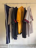 Side view of rack showing navy Adidas pants and five tops