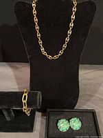 Full view of necklace on stand, bracelet on bar, earrings in box