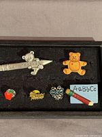 All six pins laid in display case showing overall lot