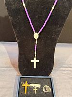 Rosary hanging on black display bust with other items in box below