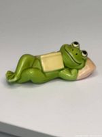 Frog figurine side view reclining on pillow