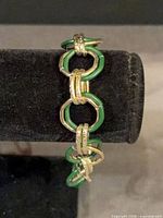Full bracelet on display, showing alternating green enamel and gold-tone links
