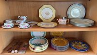 Two-shelf cabinet view showing grouped plates, tea set, miniature teapot and wooden utensils