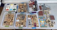Overall lot view showing bins of wood-mounted stamps, ink pads, stamp press and cling stamp sheets
