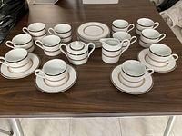 Full set arranged on table showing all cups, saucers, creamer and sugar bowl