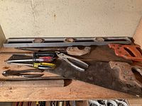 Overview of level, saws, pliers, screwdrivers, file on bench